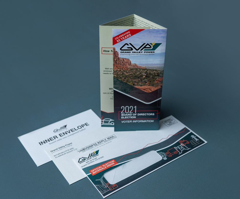 Grand Valley Power ballot for board of directors election. This direct mail package includes a quad-fold brochure, pictured standing up on top of an exterior envelope and two interior response envelopes.