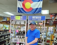 Business owner poses in liquor store with Colorado flag