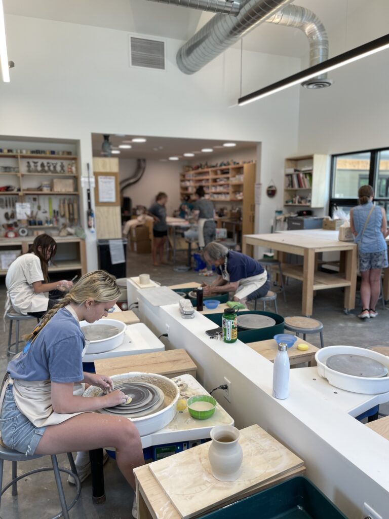 Three students working on pottery wheels in an art studio.