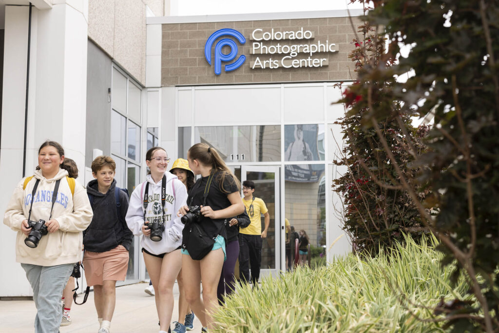 Young students holding cameras walking out of the Colorado Photographic Arts Center