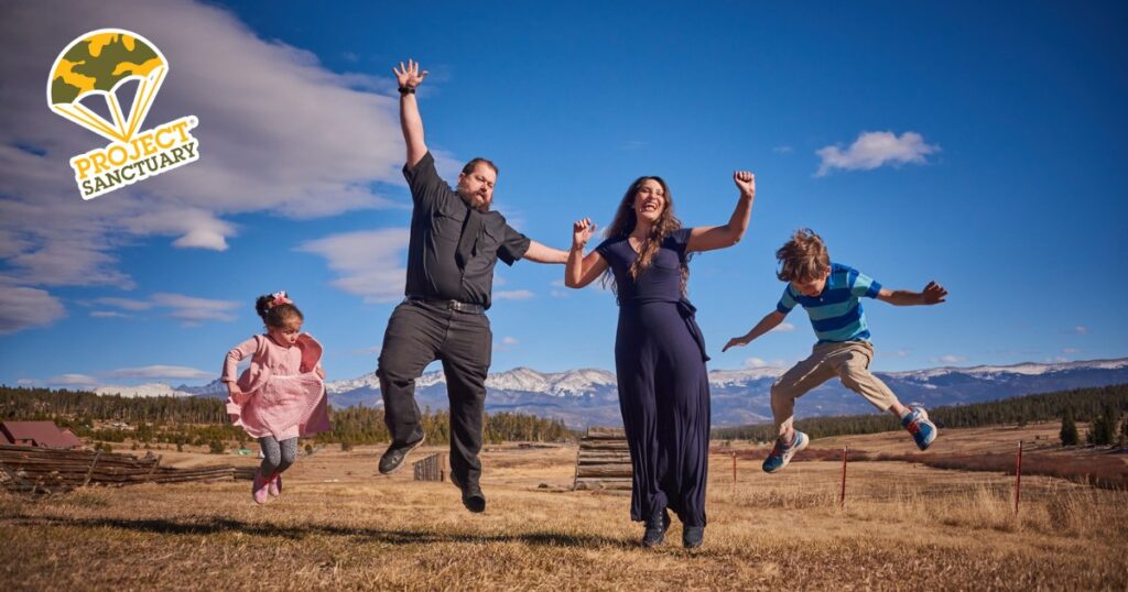 A smiling family jumping in a field.