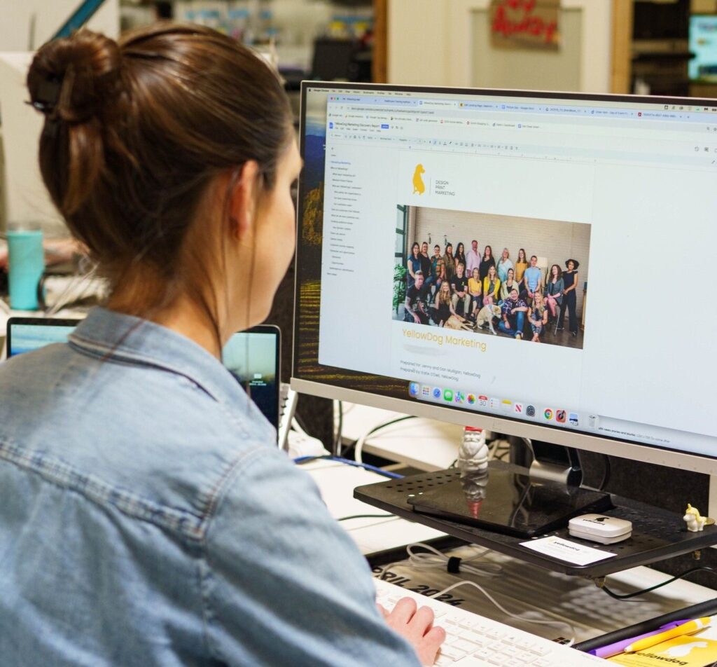 Woman at a computer writing a creative brief marketing document with YellowDog branding.