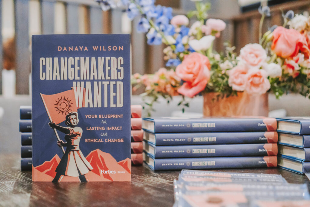 Changemakers Wanted: photo of books in front of flower bouquet.