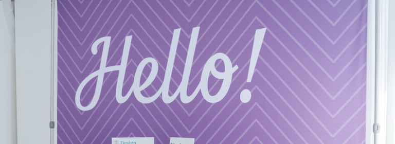 "Hello!" white cursive text on purple chevron-patterned event display backdrop.