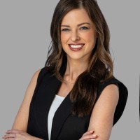 Young woman with brown hair and crossed arms smiling at the camera